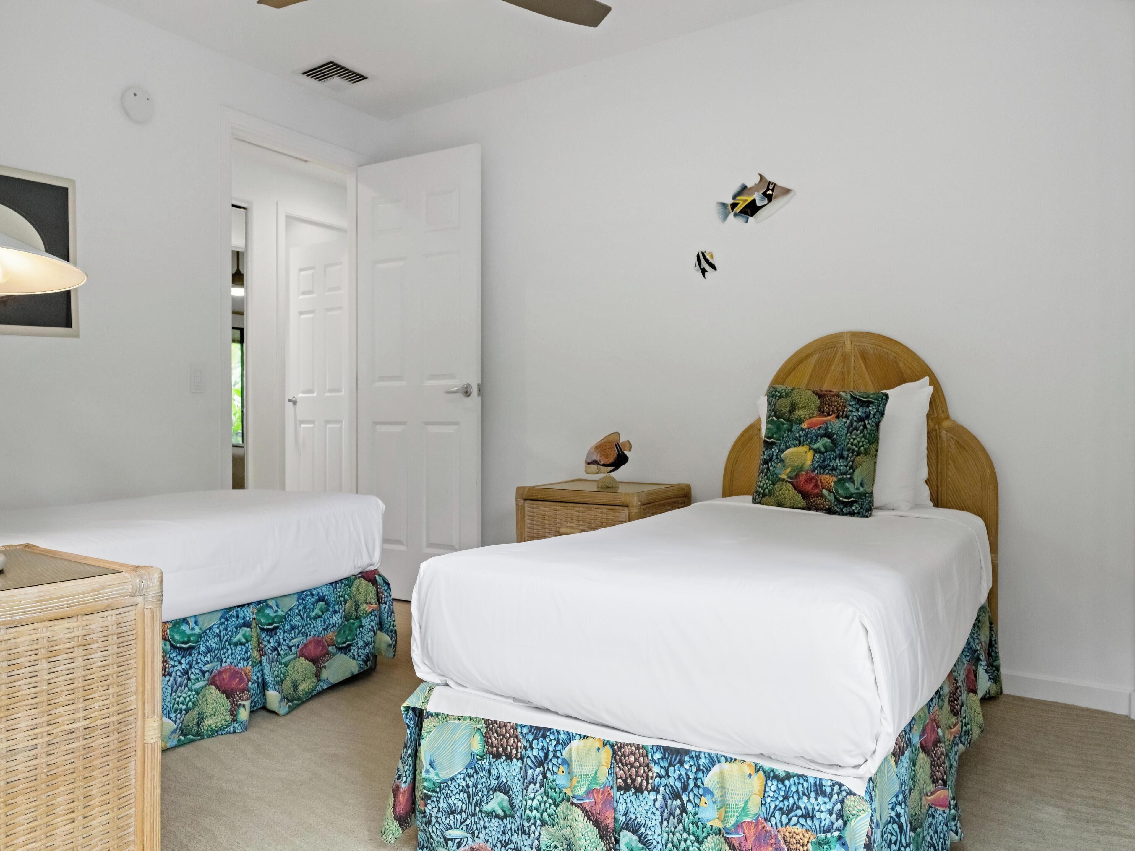 A bedroom with two beds, a nightstand, and a wall-mounted shelf.