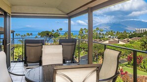 Ein Balkon mit Tisch und Stühlen, der einen schönen Blick auf das Meer und die Berge bietet.