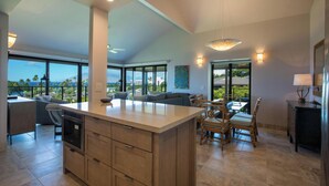 Uma cozinha espaçosa com uma ilha grande, armários modernos e vista para o mar.
