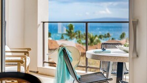 Ein Balkon mit Blick auf den Ozean, ein runder Tisch mit einem Notizbuch und Korbstühle.