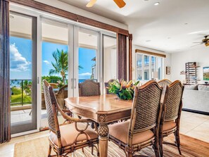 Un coin repas avec une table et des chaises, une vue sur l’océan et un balcon doté d’une balustrade.