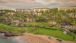 Un resort con varias edificaciones, una playa y palmeras.
