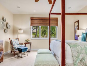 Une chambre à coucher avec un lit à baldaquin, un coin salon avec un fauteuil et un banc, une petite table avec une lampe, et une fenêtre donnant sur un paysage verdoyant.