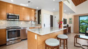 A modern kitchen with wooden cabinets, stainless steel appliances, and a central island with stools.