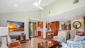 A spacious living room with a large sofa, a coffee table, and a dining area with wooden furniture. - Recently Renovated - Walk to the Beach (Wailea)