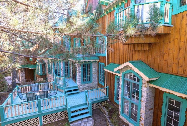 A multi-level wooden house with stone walls and turquoise accents, featuring multiple balconies and windows.