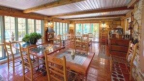 Un intérieur rustique en bois, avec une grande table à manger, des chaises et une cheminée.