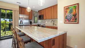 Een moderne keuken met houten kastjes, een marmeren eiland en barstoelen.