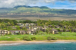 Une station balnéaire dotée de villas en bord de mer, d’une végétation luxuriante et d’un paysage montagneux en toile de fond.