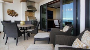 Un espace repas extérieur moderne, aménagé avec des meubles en osier et doté d’un barbecue.