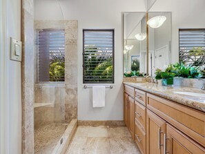 A modern bathroom with a glass shower enclosure, a large mirror, and wooden cabinetry. - Walk to Waves, Snorkeling, Pool - Wailea Elua 910 (Wailea)