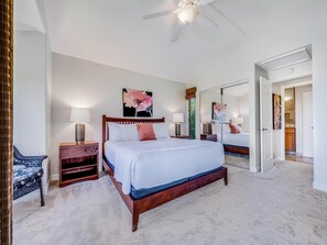 A spacious bedroom with a large bed, bedside tables, a ceiling fan, and a mirror. - Walk to Waves, Snorkeling, Pool - Wailea Elua 910 (Wailea)