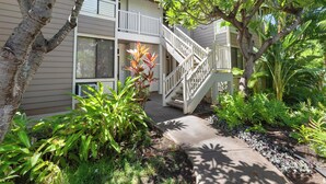 A two-story building with a white exterior, a balcony, and a staircase leading to the upper floor. - Quiet Retreat Between Fairways - Grand Champions 140 (Wailea)