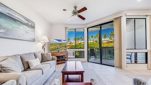 A spacious living room with a sofa, coffee table, and a television displaying a scenic view.