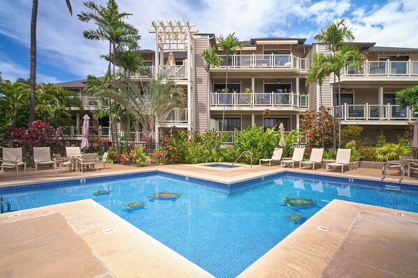 A hotel with a swimming pool, palm trees, and lounge chairs.