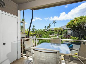 Un balcón con una mesa y sillas, con vista a una zona residencial con palmeras y casas.