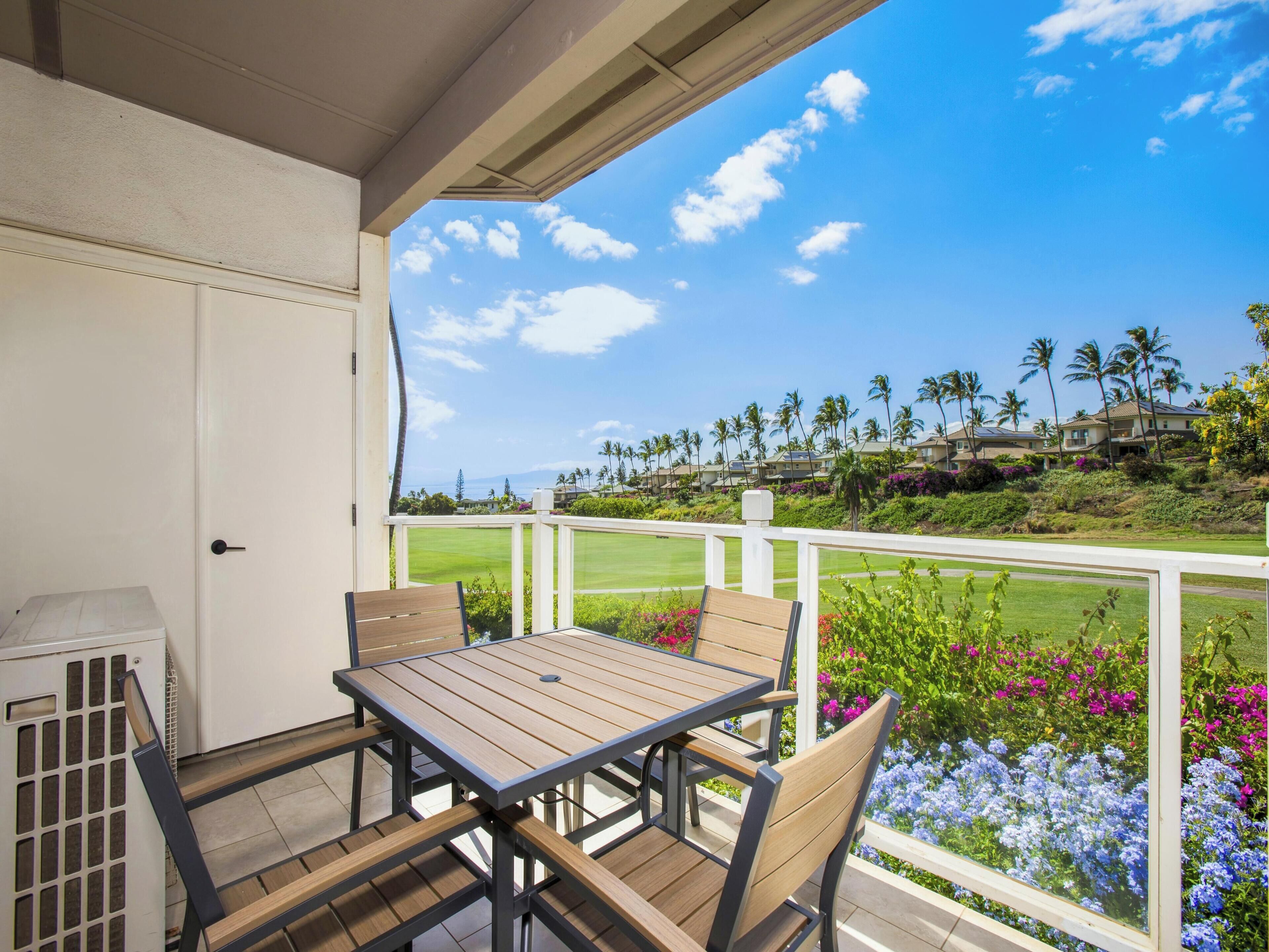 A covered outdoor area with a table and chairs, a white door, and a view of a golf course and houses.