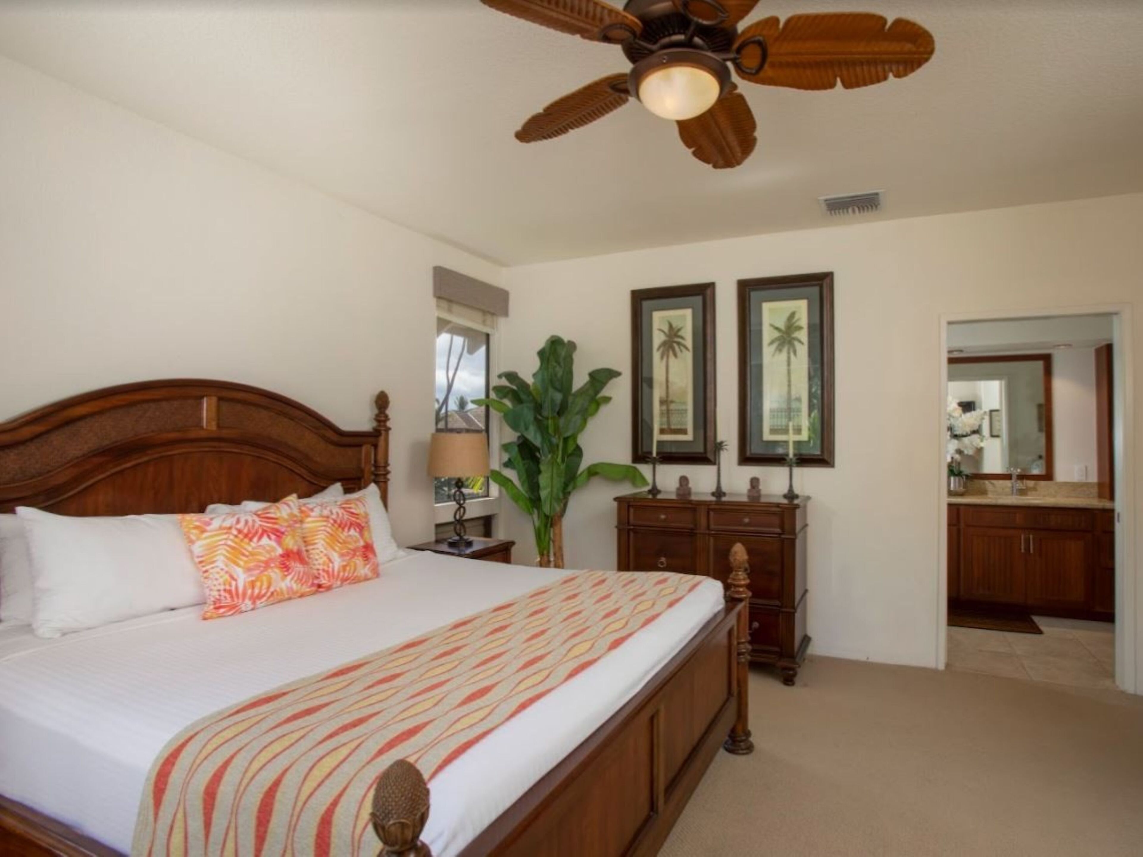 A bedroom with a large bed, a ceiling fan, a nightstand, a dresser, and a mirror.