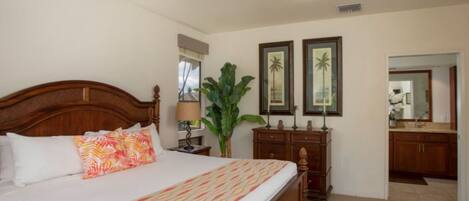 A bedroom with a large bed, a ceiling fan, a nightstand, a dresser, and a mirror.