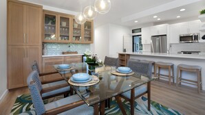 Une cuisine moderne avec des meubles en bois, une table à manger en verre et des tabourets de bar.