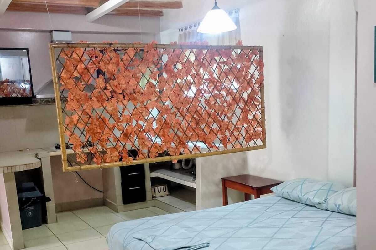 A bedroom with a bed, a desk, and a chair.