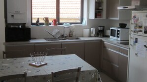 A compact kitchen with a dining table, a refrigerator, a microwave, and a coffee maker. - Pen Ty lumineux avec jardinet clos, en plein cœur de la côte de granit rose (Trégastel)