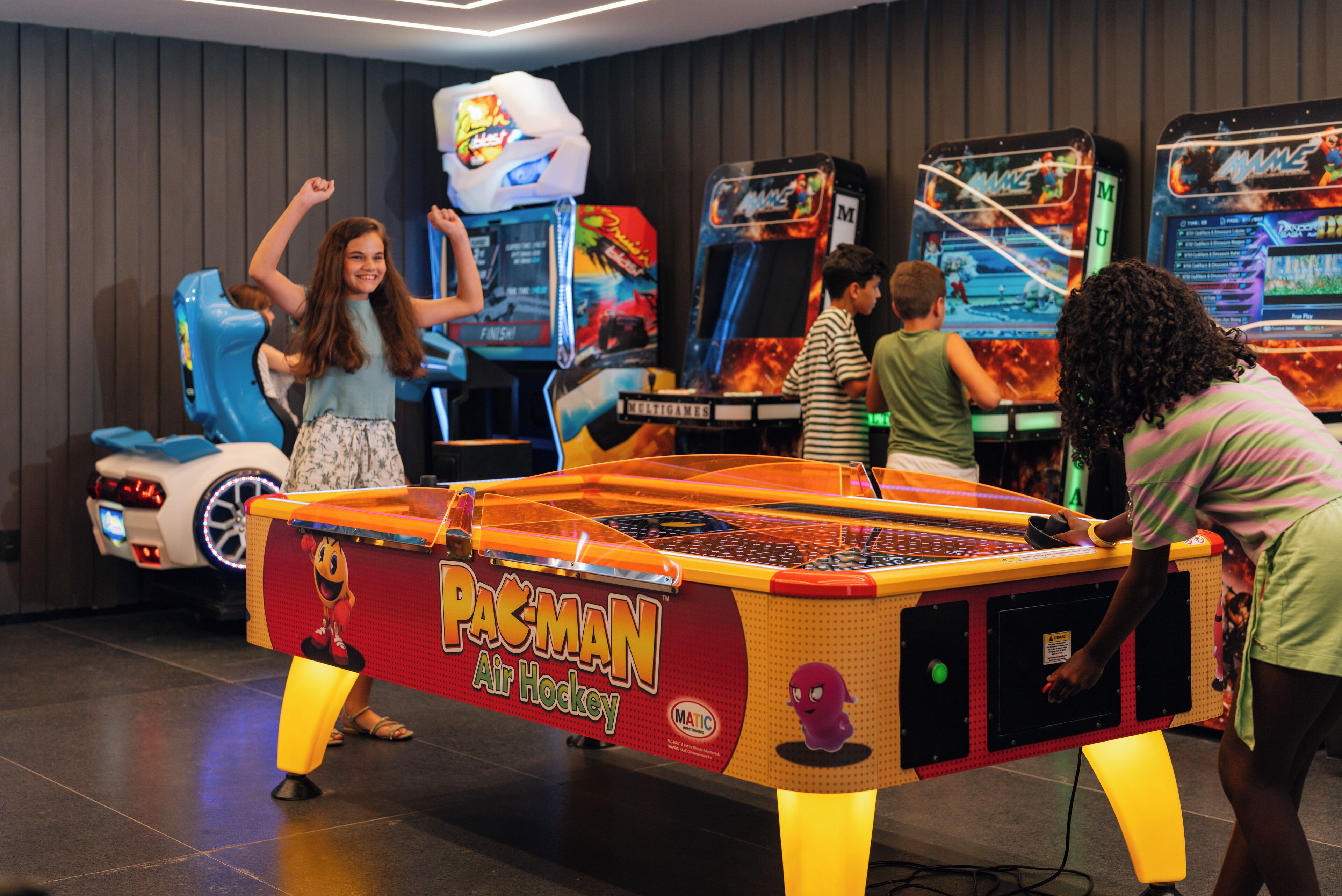 Een Pac-Man luchthockeytafel in een ruimte met andere spelautomaten.