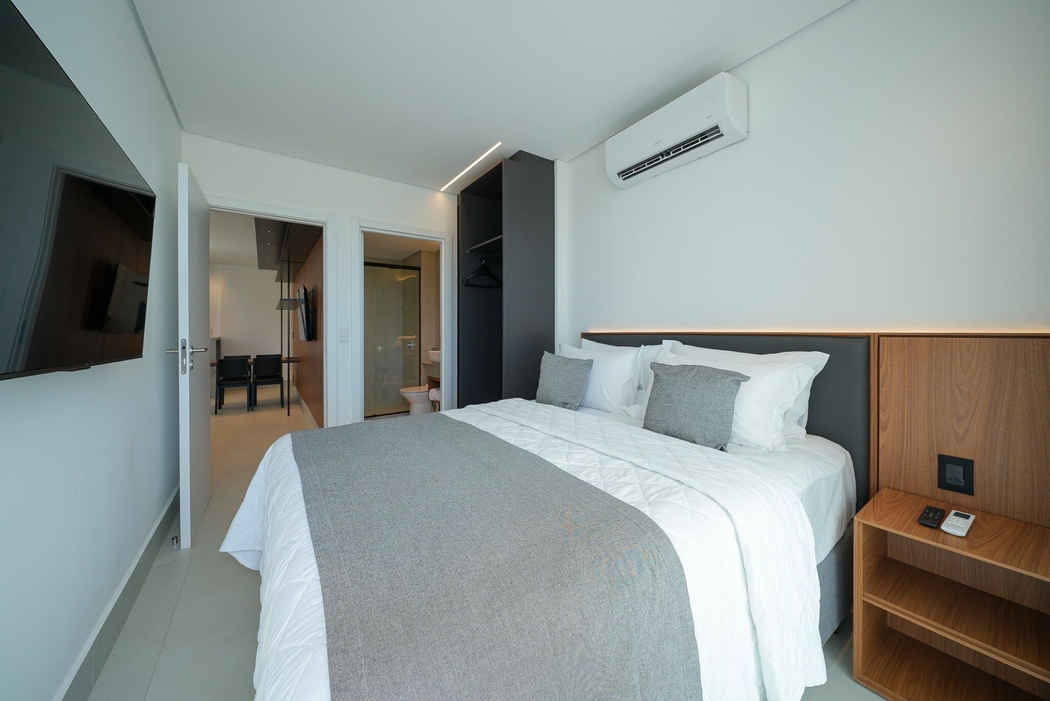 Una habitación de hotel moderna con una cama grande, una mesita de noche con un teléfono y un armario.