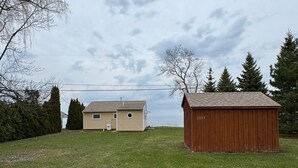 A house with a small shed and a grassy yard. - Lake it Easy 2-bedroom cottage in Lyndonville (Lyndonville)