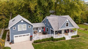 Une maison à deux étages avec un garage, une véranda et une pelouse bien entretenue.