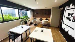 A modern office space with two white tables, black chairs, a sofa with cushions, a potted plant, and a wall with a motivational poster. - Luxurious brand new Apt in the heart of miraflores (Lima)