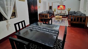 A dining area with a black table and chairs, a ceiling fan, and a television in the background.