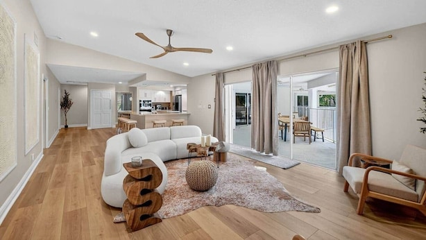 A spacious living area with a large white sectional sofa, a wooden coffee table, and a ceiling fan.
