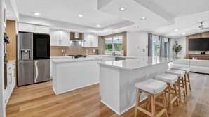 A modern kitchen with a central island, stainless steel appliances, and a large window overlooking greenery.
