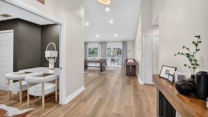 A modern interior with a wooden floor, a pool table, and a bar area.