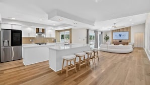 A modern kitchen with a central island, stainless steel appliances, and a seating area with a sofa and bar stools.