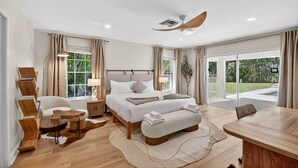 A spacious bedroom with a large bed, a desk, and a view of the outdoors.