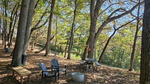 A campsite with two Adirondack chairs, a picnic table, a metal fire ring, and a sign indicating a location reservation. - Hocking Hills Store Campsite #3 (Tent Site) (Washington Township)