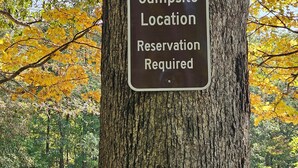A sign on a tree indicating a campsite location with a reservation requirement. - Hocking Hills Store Campsite #3 (Tent Site) (Washington Township)