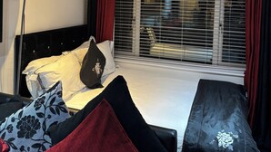 Quarto de hotel moderno com uma cama, mesa de cabeceira, luminária e janela com persianas.