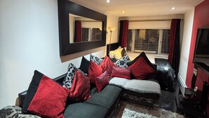 Uma sala de estar moderna com um sofá seccional, um espelho grande e uma televisão de tela plana.