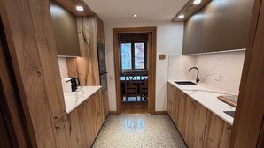 A narrow hallway with wooden cabinets and a granite floor, leading to a door with a view of a balcony. - Apartment in the old village, at the foot of the slopes. Residence le SQUAW VALLEY (Val-d'Isère)