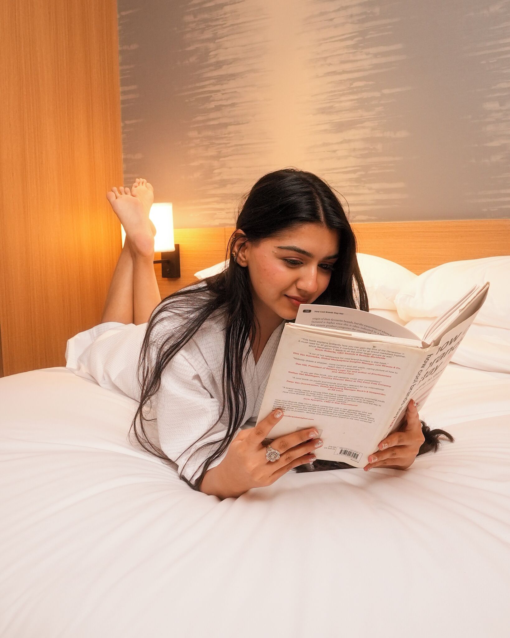 A person lying on a bed, reading a book.