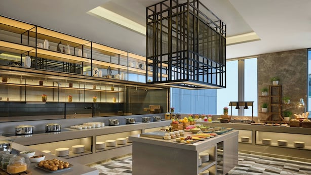 Una cocina moderna con varias encimeras, estantes con utensilios de cocina y una isla central con alimentos.