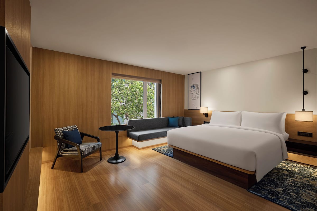 Habitació d'hotel moderna amb un llit gran, un sofà, una taula petita i una televisió.