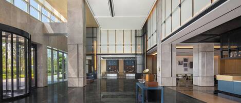 A spacious lobby with a marble floor, large windows, and a reception desk.