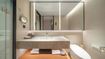 Un baño moderno con lavamanos de mármol, un espejo grande y un inodoro.