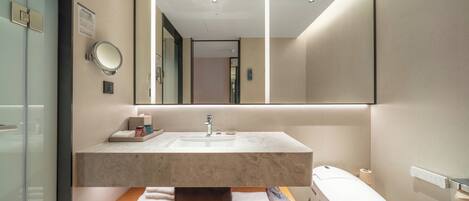 A modern bathroom with a marble sink, a large mirror, and a toilet.