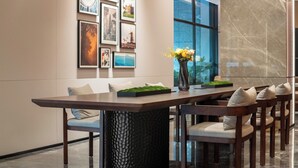 A modern dining area with a long table, chairs, and a vase with flowers.