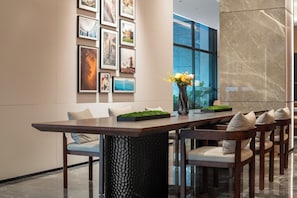 Un espace repas moderne avec une longue table, des chaises et un vase rempli de fleurs.